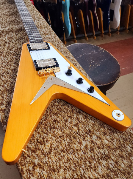 An Epiphone 1958 Korina Flying V at Arthur’s Music Store, featuring a natural wood finish, white pickguard, and gold-colored hardware.