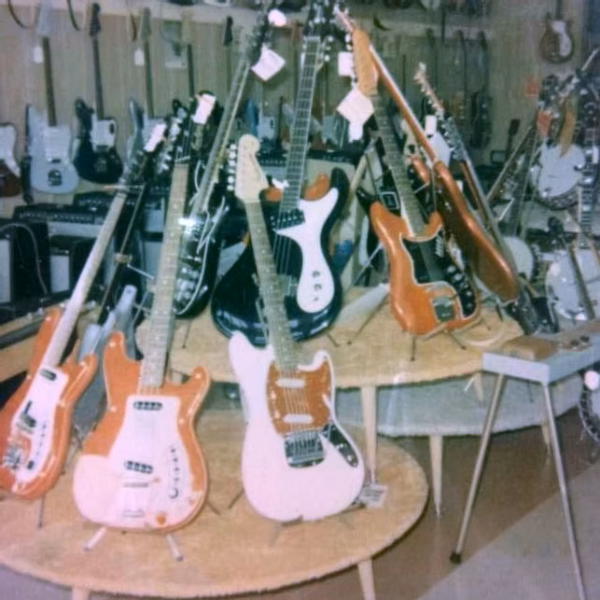 Arthur’s Music Store during the surf music era, with electric guitars and basses filling the showroom’s tables and walls.