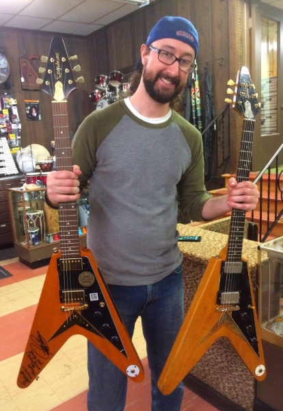 Steve Krider holds two generations of “Amos” at Arthur’s Music Store: the 2018 Epiphone Limited Edition Joe Bonamassa signature model at left and the original 1958 Gibson Flying V at right.